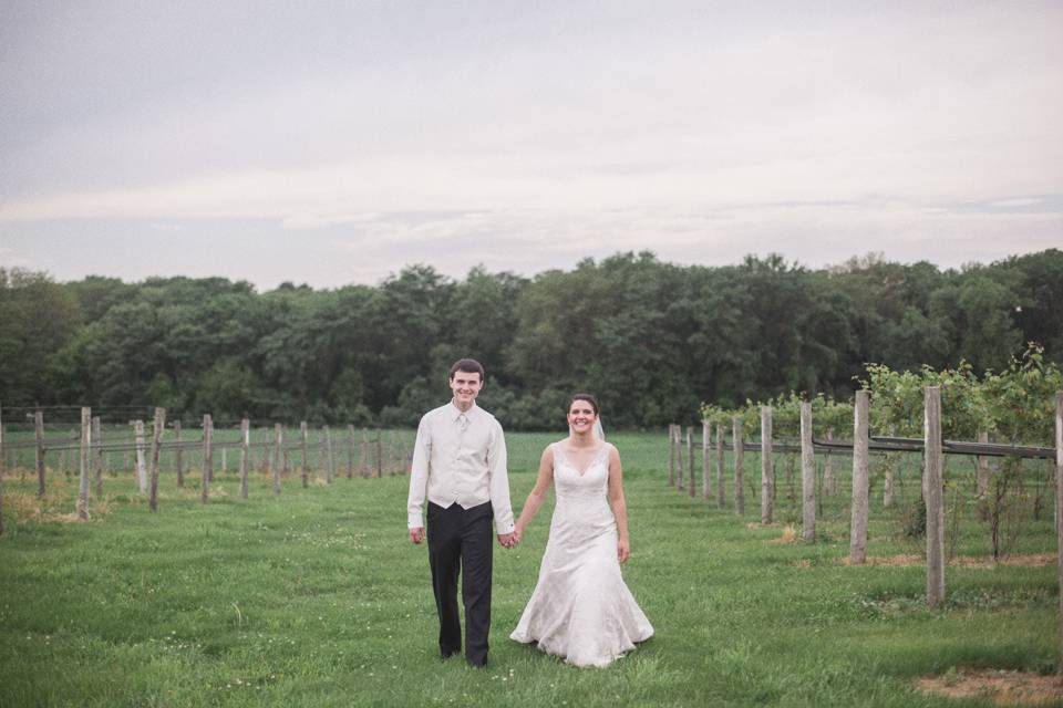 bride and groom walking holding hands in winery