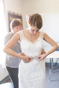 Mother of bride helping her daughter put on beaded belt