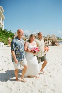 two brothers walking sister down the aisle for her beachside wedding