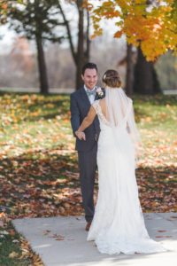 bride and groom seeing each other for the first time outside near colorful fall trees