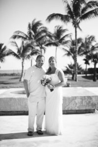 black and white film photo of bride and groom in front of fountain at beach resort