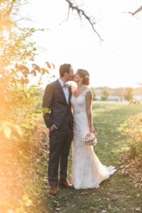 bride and groom kissing at sunset at the edge of wooded area