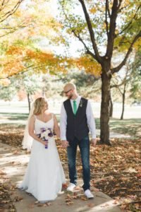 Bride and groom walking through fall colored trees